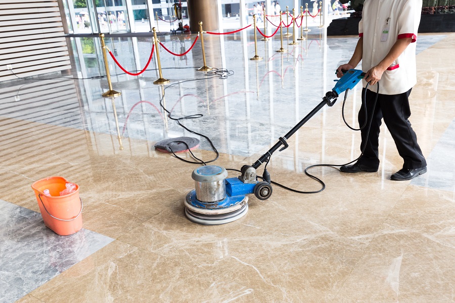 Person polishing the floor indoors for a commercial cleaning company.